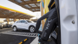 Electric car parked at a charging bay in a car park, connected to a charging station