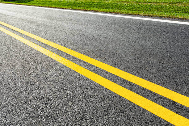 Freshly painted white road line markings on asphalt to improve traffic safety and visibility
